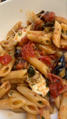 pasta with tomatoes, olives and sauce in a white bowl