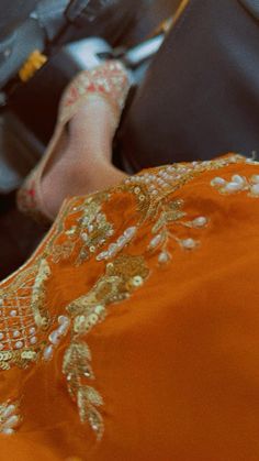 a woman in an orange dress sitting on a couch with her feet propped up against the back of a chair