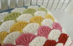 a crocheted blanket sitting on top of a white table next to a chair