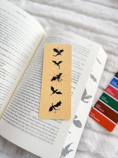 a bookmark with bats on it sitting next to an open book