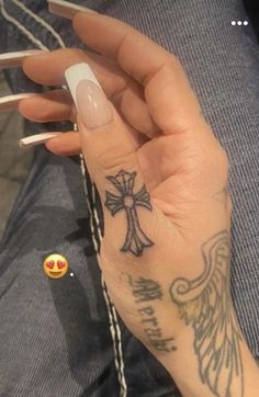 a woman's hand with a cross tattoo on it