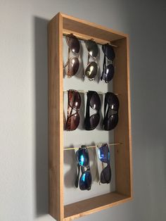 a wooden display case with sunglasses hanging from it's sides and on the wall