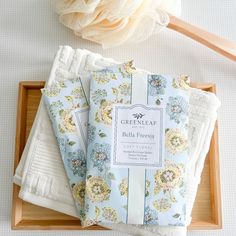 three folded napkins sitting on top of a wooden tray next to a white flower