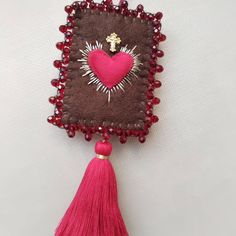 a heart shaped brooch with tassels and beads hanging from it's side