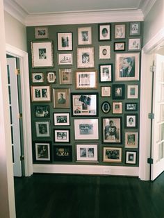 a wall with many framed pictures on it in a room that has wood floors and hard wood flooring