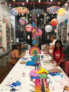 children are sitting at a table with paper decorations and crafting supplies on the table