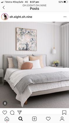 a bed with white sheets and pillows in a bedroom next to a painting on the wall