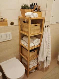 a wooden shelf filled with towels and other items in a bathroom next to a toilet