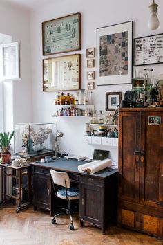 an old desk in the corner of a room with lots of pictures on the wall