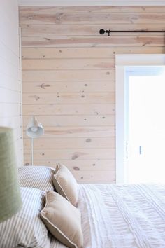 a bedroom with wood paneling on the walls and bed in front of a window