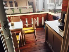 an outdoor kitchen and dining area on a balcony with wooden floors, brick walls, and floor to ceiling windows