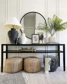 a black table with two stools and a mirror on the wall behind it,