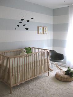 a baby's room with striped walls and a rocking chair in front of the crib