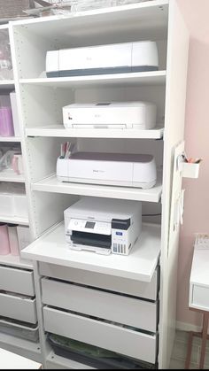 there is a white shelf with printer and other items on it in the room that has pink walls