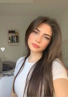 a woman with long brown hair is posing for the camera