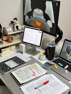 a desk with two laptops and a computer monitor on it, along with other office supplies