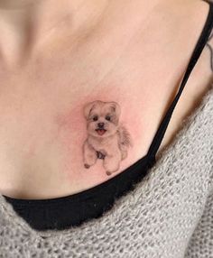 a woman's chest with a small dog tattoo on her left side ribcage