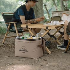 two people sitting at a picnic table with coolers and drinks in front of them