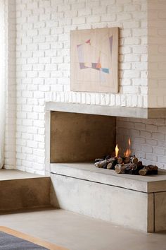 a white brick fireplace in a living room next to a painting on the wall above it