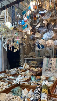 an assortment of jewelry and necklaces in a market stall with lots of hanging items