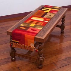 a wooden bench with a multicolored table runner on it's seat cover