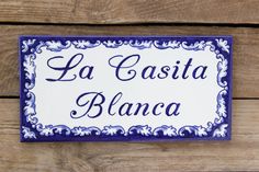 a blue and white sign that says la casita blancca on the side of a wooden wall