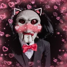 a creepy doll wearing a suit and red bow tie with hearts around her eyes in the background