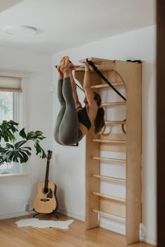 a woman hanging upside down on a hammock in a room with wood floors