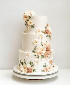 a three tiered wedding cake with flowers on the top and bottom, sitting on a white plate