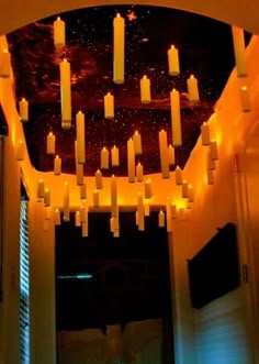 a room filled with lots of lit candles hanging from it's ceiling above a doorway