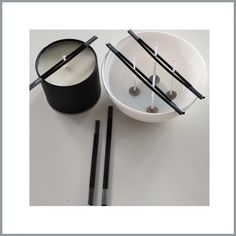 two black and white bowls with chopsticks next to each other on a table