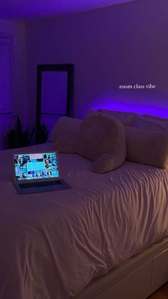 a laptop computer sitting on top of a bed in a room with purple lights above it