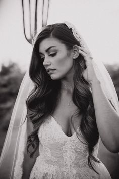 a woman in a wedding dress is holding her veil over her head and looking at the camera