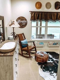 a baby's room with a rocking chair, window and cow hide rug on the floor