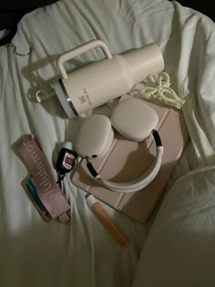 the contents of a woman's purse are laid out on a white bed sheet