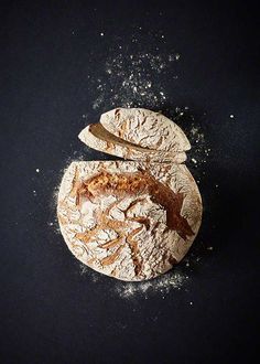 an uncooked pizza sitting on top of a black table covered in powdered sugar