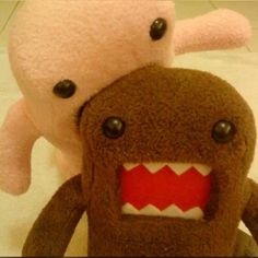 two stuffed animals with mouths open on a white surface, one is pink and the other is brown