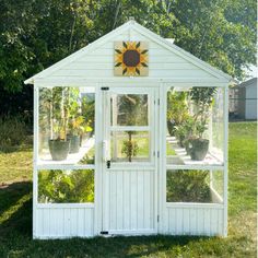 a small white shed with sunflowers on the top