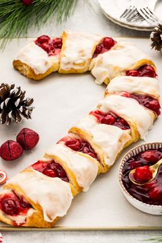 a pastry with white icing and raspberries on it next to christmas decorations