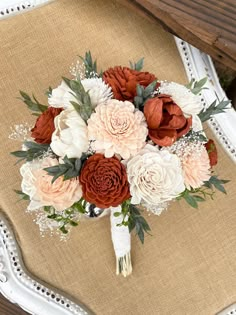 the bridal bouquet is sitting on top of an old chair with white and orange flowers