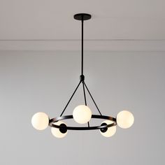 a black chandelier with five white balls hanging from it