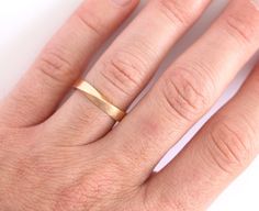 a woman's hand with a gold wedding ring on top of her left hand