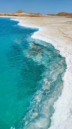 the water is very clear and blue in this beach scene with white foam on the sand