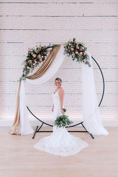 a woman standing in front of an arch with flowers on it