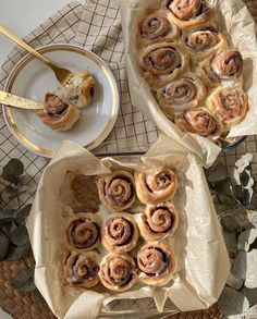 two trays filled with cinnamon rolls on top of a table next to a plate