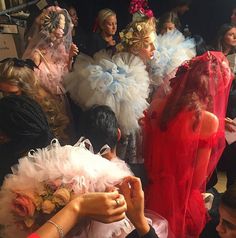 a group of people standing around each other wearing dresses and veils on their heads