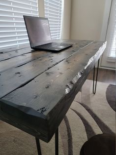 an open laptop computer sitting on top of a wooden table in front of a window