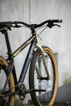 a bike parked next to a building on the side of the road with yellow rims