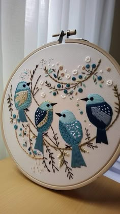 two blue birds sitting on top of a wooden table next to a white wall hanging