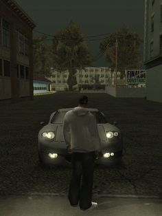 a man standing next to a car on a street in the dark night with buildings behind him